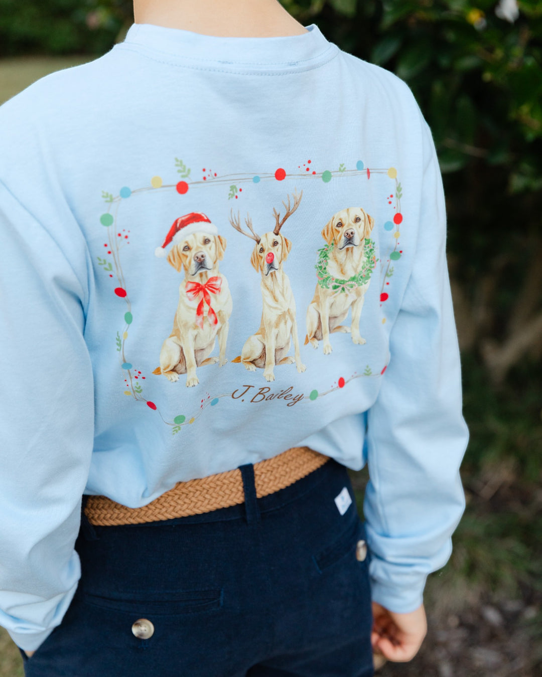 Light blue sweatshirt with Christmas-themed dog illustrations worn by a person.