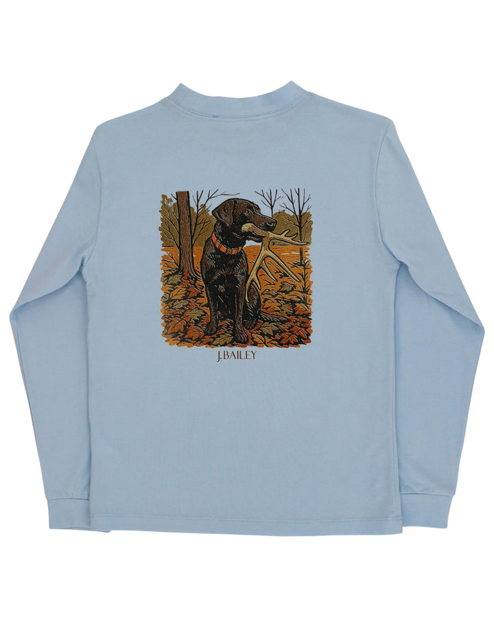A light blue long-sleeve t-shirt with a large graphic print on the back featuring a black Labrador retriever holding a hunting rifle in an autumn forest, with the text &