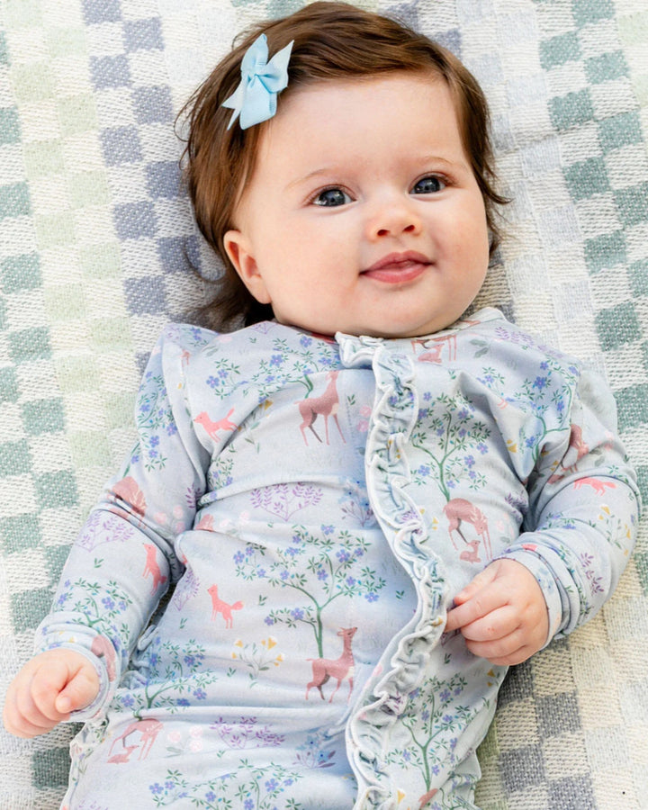 Baby wearing a floral outfit lying on a checkered blanket