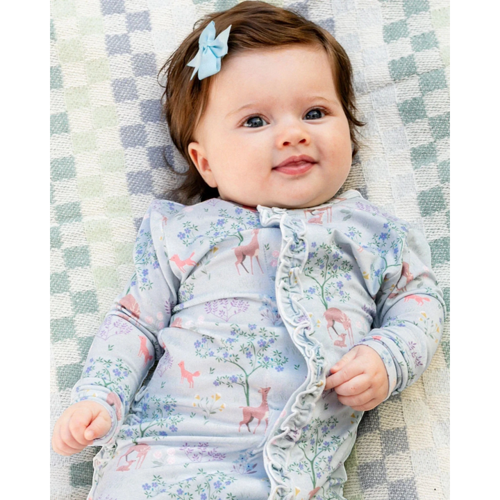 Baby wearing a floral outfit lying on a checkered blanket