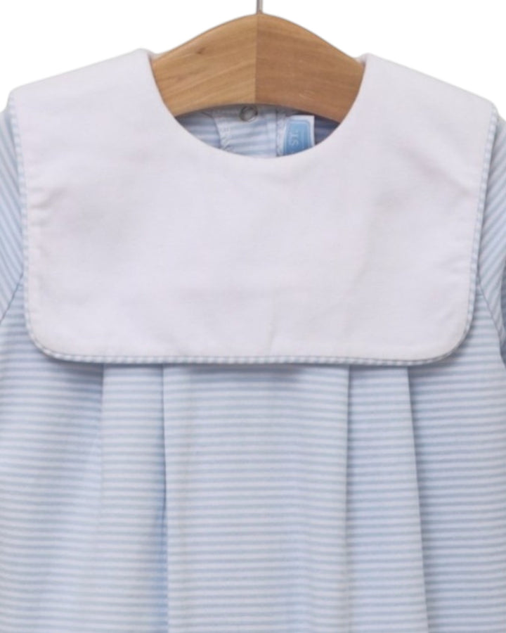 A close-up of a baby dress or romper with a wide white bib collar and light blue and white horizontal stripes, hanging on a wooden hanger against a white background, that store