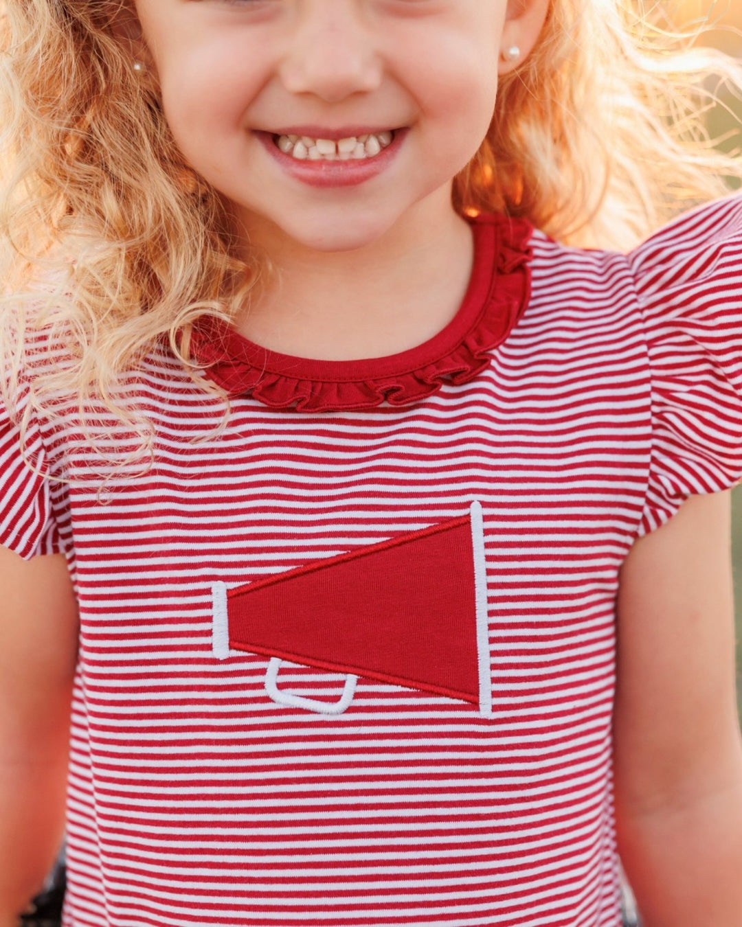 Child wearing a red and white striped dress with a red pocket detail.
