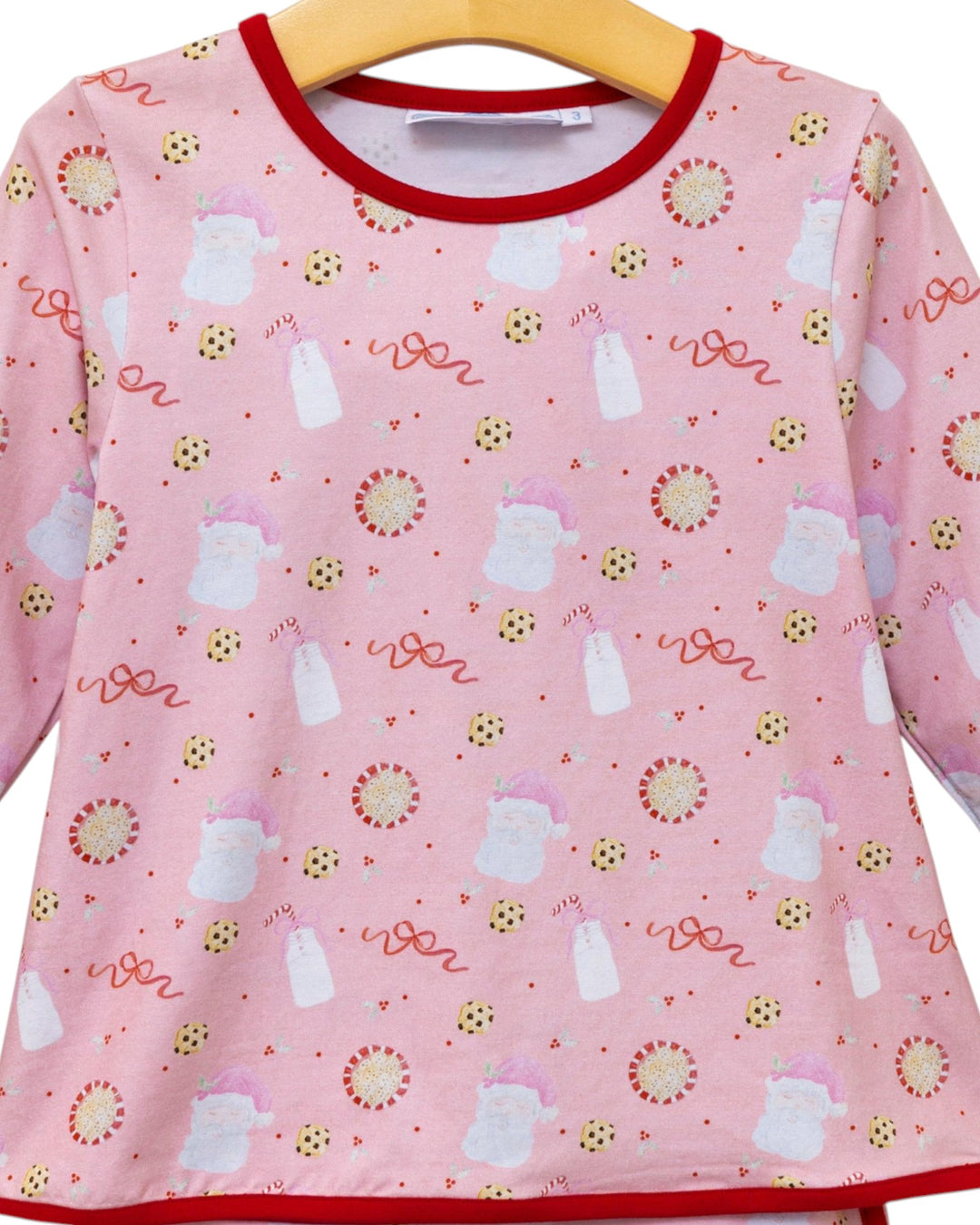 Pink children's shirt with cartoon designs on a hanger