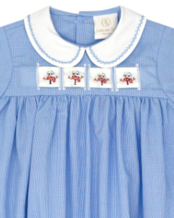 A close-up of a light blue gingham dress featuring a white Peter Pan collar with blue trim, four embroidered snowman patches across the chest, and a visible Lullabong brand label inside the collar, that store