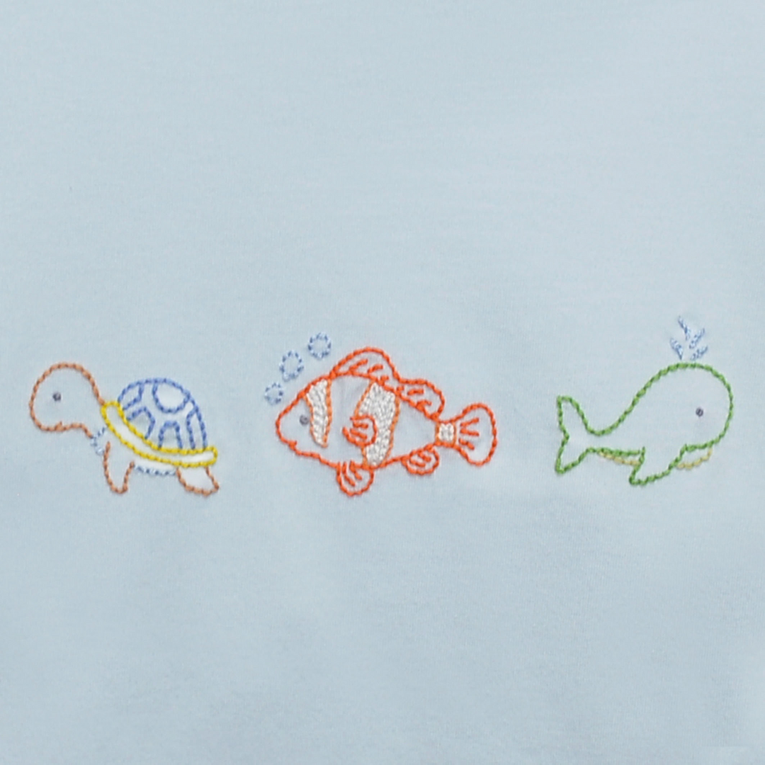 Embroidered designs of a turtle, fish, and whale on a light blue background