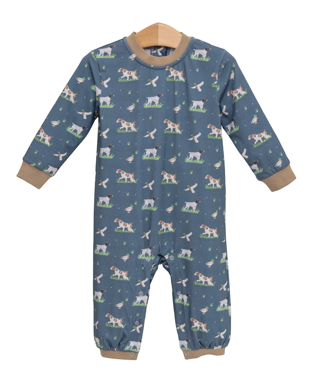 A baby long-sleeve footless one-piece romper in slate blue, featuring an all-over print of dogs and cats in a grassy field, with tan ribbed cuffs and collar, hanging on a wooden hanger against a white background, that store