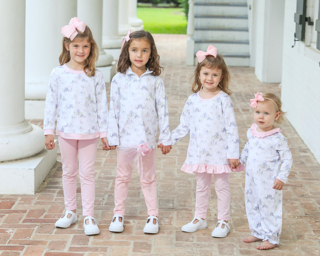 Four young girls in matching outfits standing on a brick path.