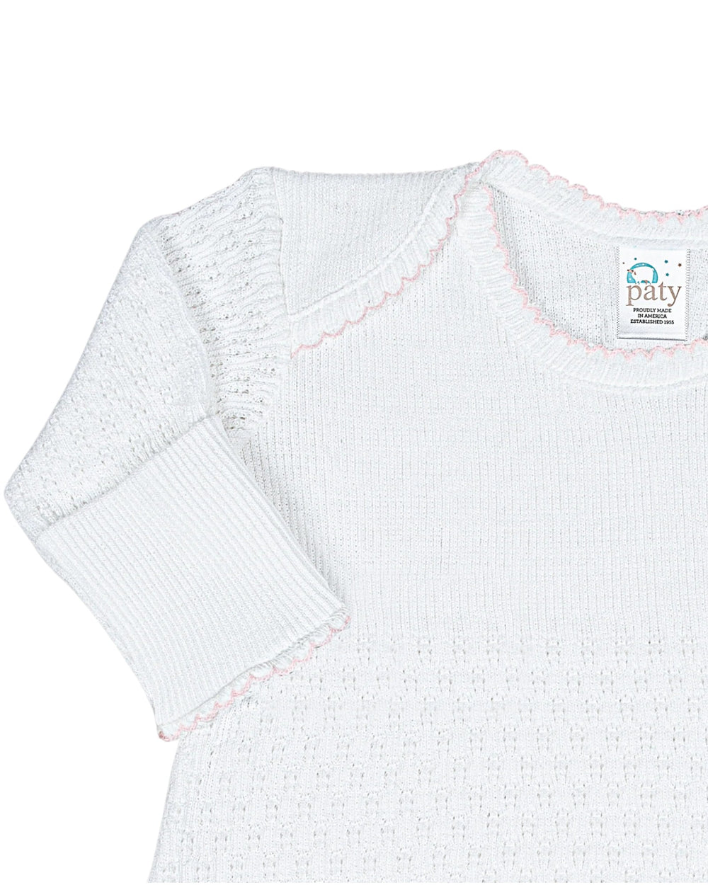 White baby sweater with pink accents on a white background