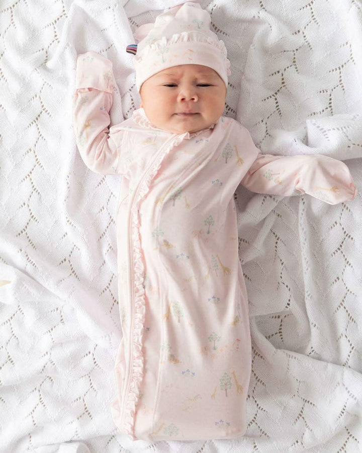 Baby wrapped in a pink swaddle with a matching hat on a white textured blanket