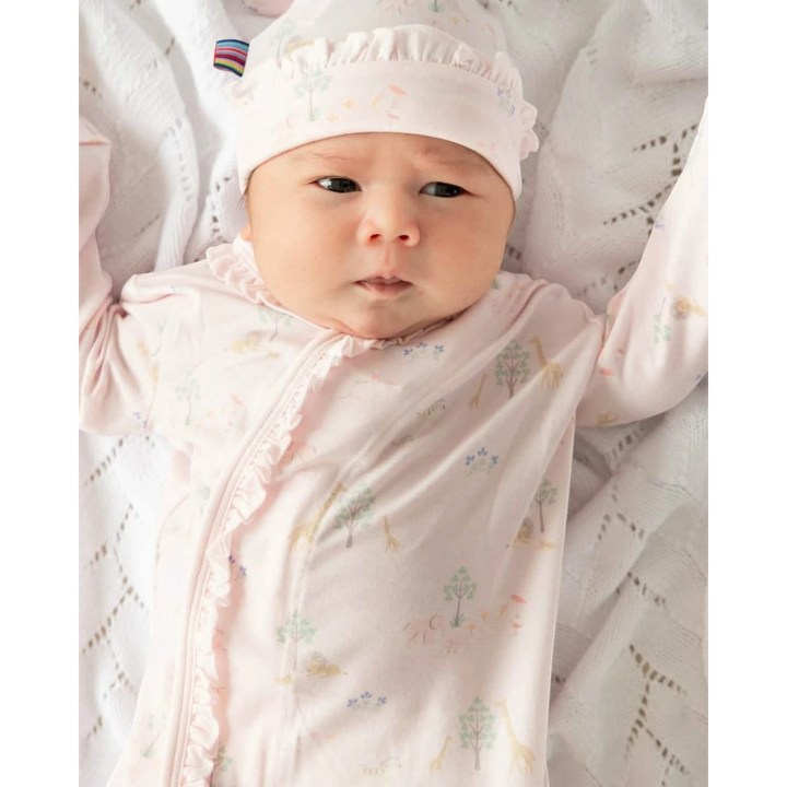 Newborn baby wrapped in a pink blanket with a white hat, lying on a textured surface.