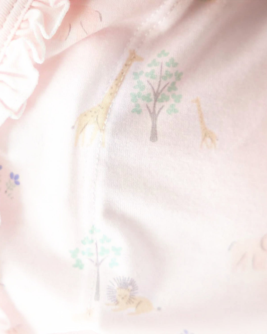 Baby blanket with giraffe and tree pattern on a pink background