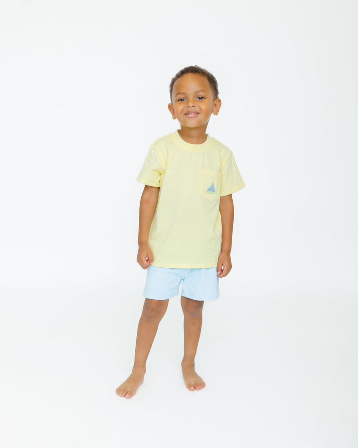 Child wearing a light yellow t-shirt and light blue shorts on a white background