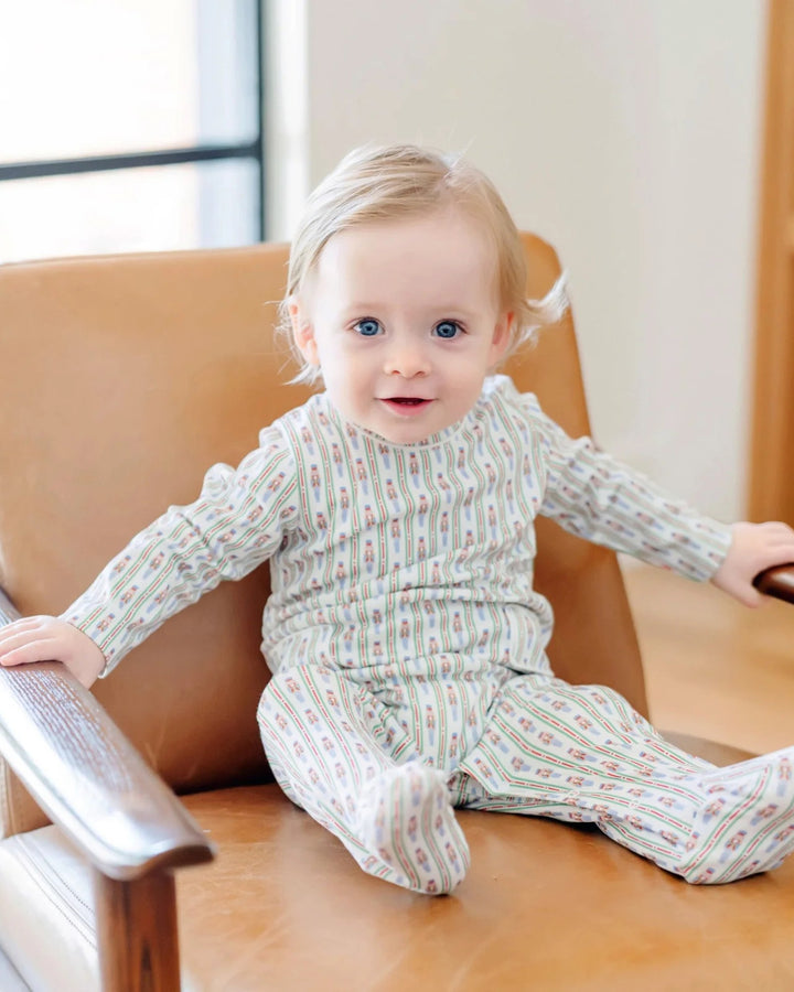 Baby in a patterned outfit sitting on a chair with a book