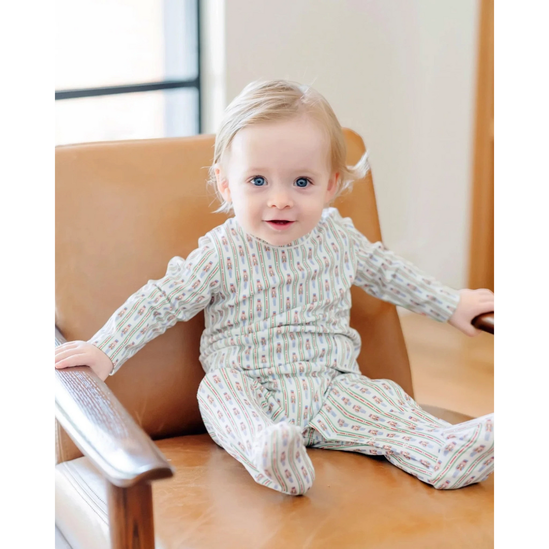 Baby in a patterned outfit sitting on a chair with a book