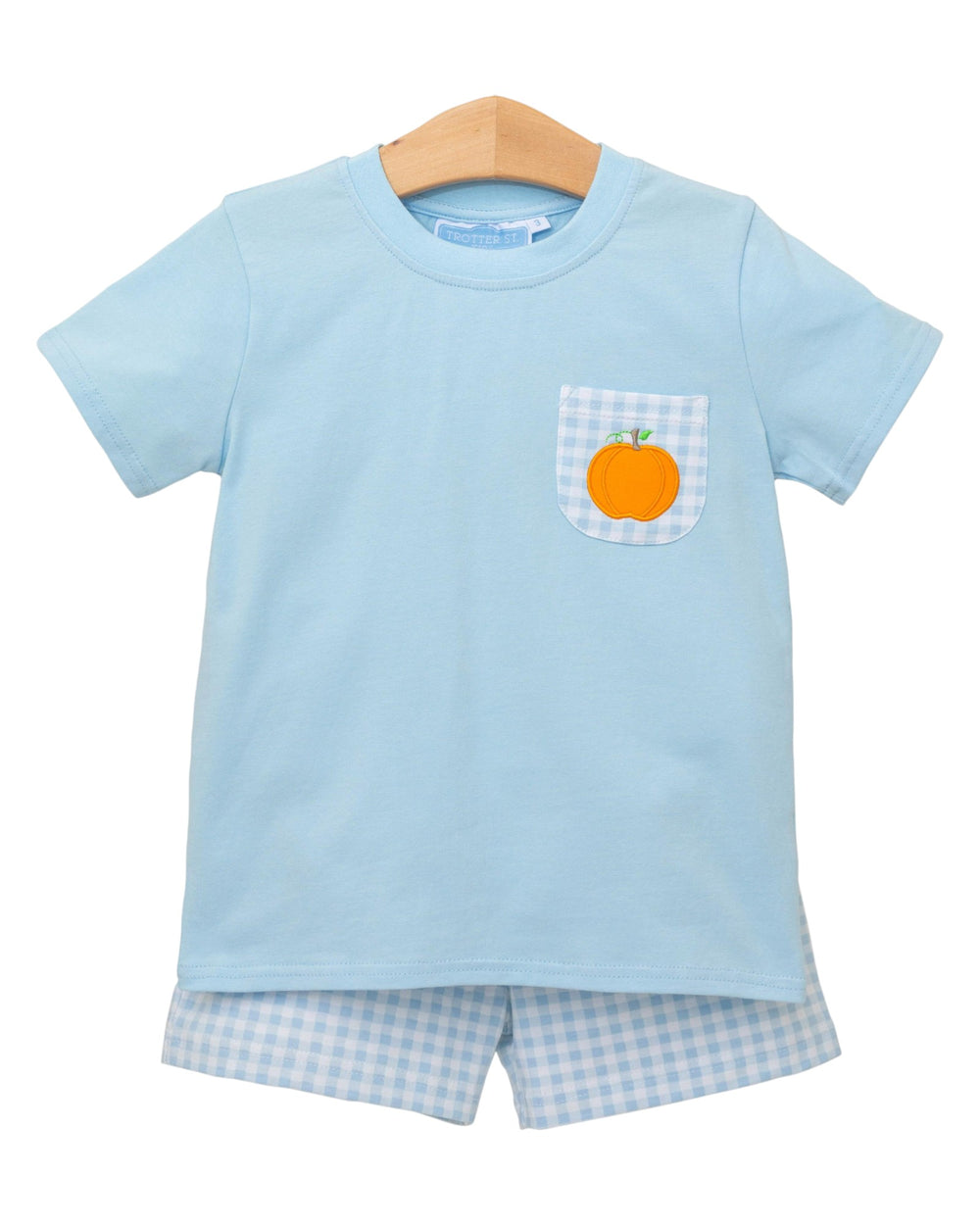 Light blue t-shirt with a pocket featuring an orange pumpkin on a hanger against a white background