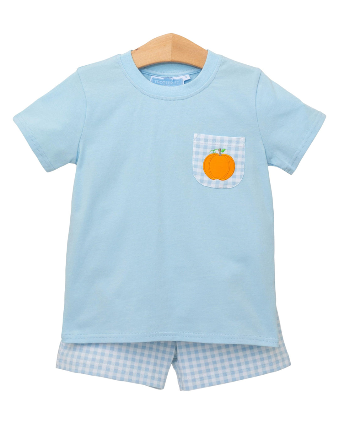 Light blue t-shirt with a pocket featuring an orange pumpkin on a hanger against a white background