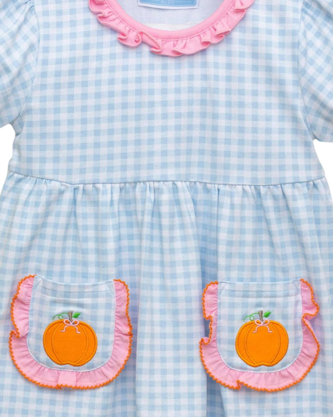 Light blue checkered dress with pink ruffled collar and orange pumpkin appliqués on a white background
