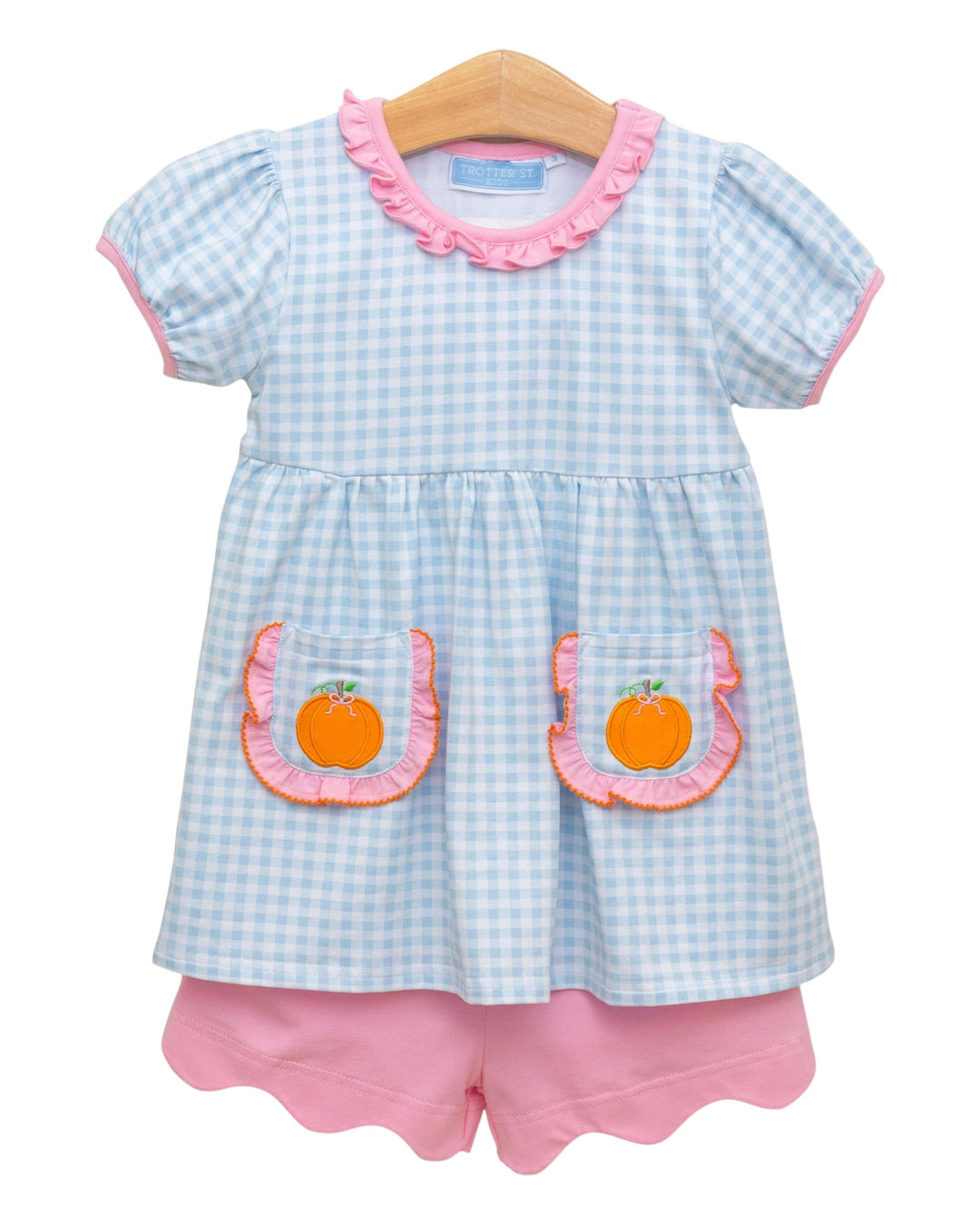 Children's outfit with checkered top and pink shorts on a white background