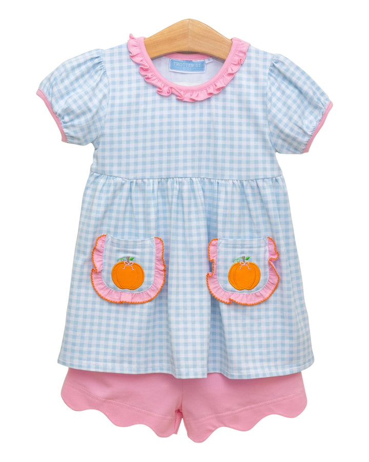 Children's outfit with checkered top and pink shorts on a white background