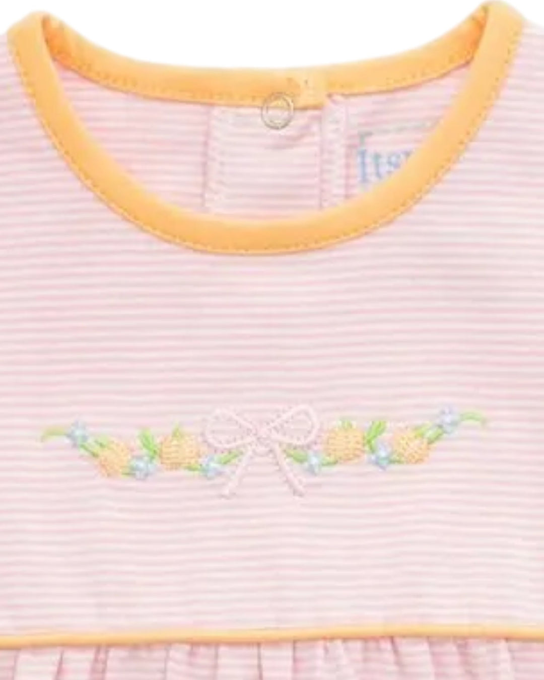 Close-up of a baby dress with light pink and white horizontal stripes, a yellow-orange crew neck trim, and a floral embroidered motif with a bow on the chest, that store