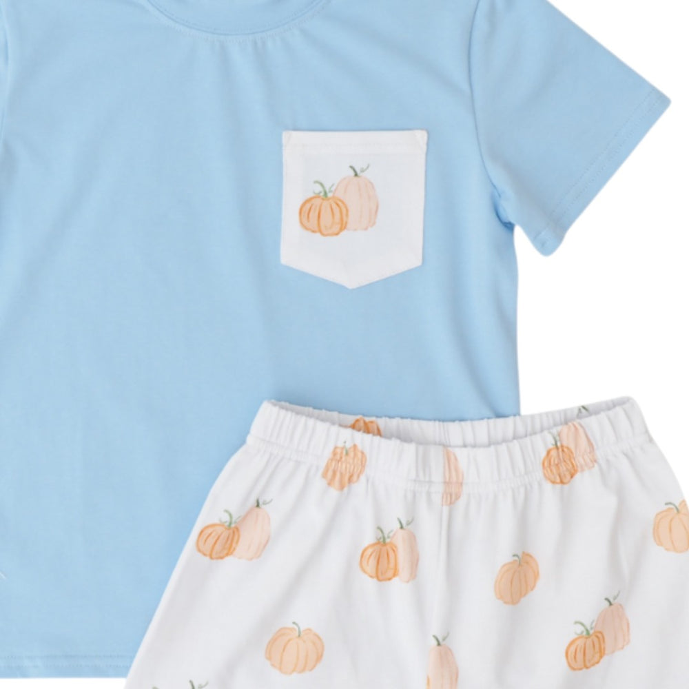A two-piece children's outfit set featuring a light blue short-sleeve top with a white chest pocket printed with orange pumpkins, and matching white shorts with an all-over pumpkin print, that store