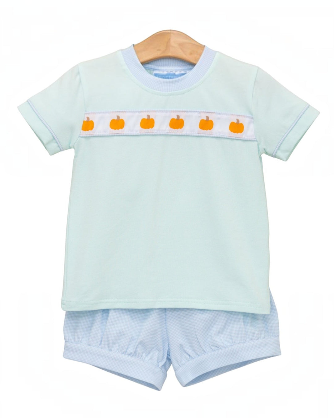 Baby short-sleeve t-shirt and matching bloomers set in pale mint green, featuring a horizontal white chest stripe with orange pumpkin motifs, displayed on a wooden hanger against a white background, that store