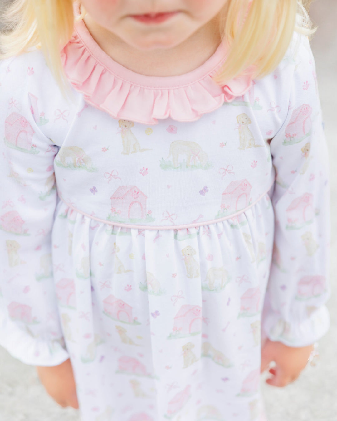 Child wearing a light purple dress with animal prints and a pink collar.