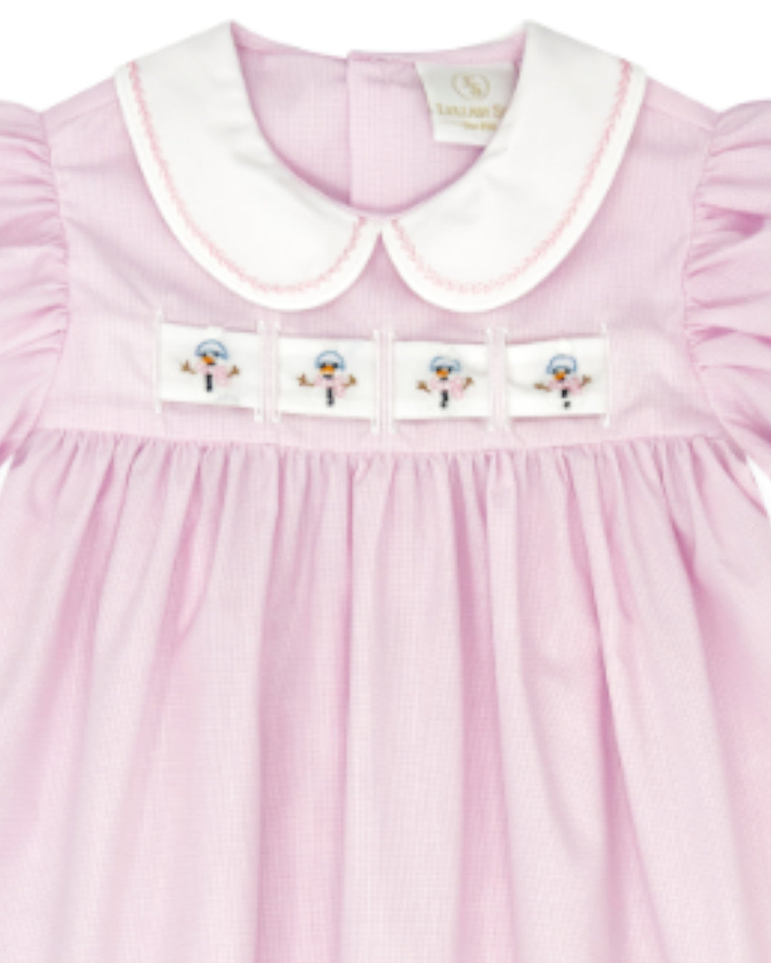 A close-up of a light pink gingham baby dress with a white Peter Pan collar, featuring four embroidered snowman patches across the chest, that store