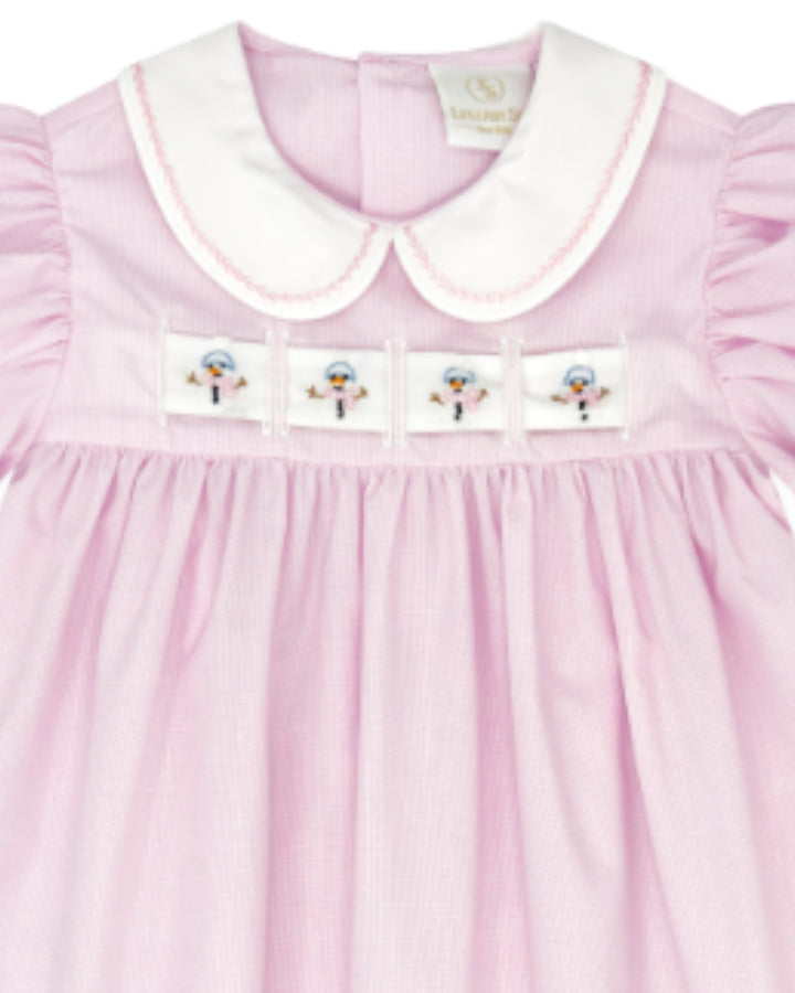 A close-up of a light pink gingham baby dress with a white Peter Pan collar, featuring four embroidered snowman patches across the chest, that store
