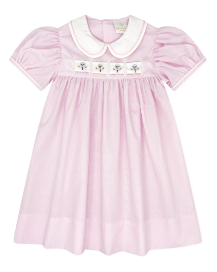 A light pink baby dress with a white Peter Pan collar, white piping on the sleeves, and a smocked chest panel featuring four embroidered flowers, that store