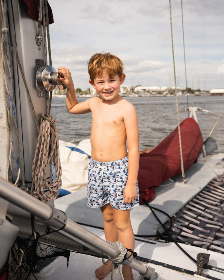 Young boy on a sailboat with water and sky in the background