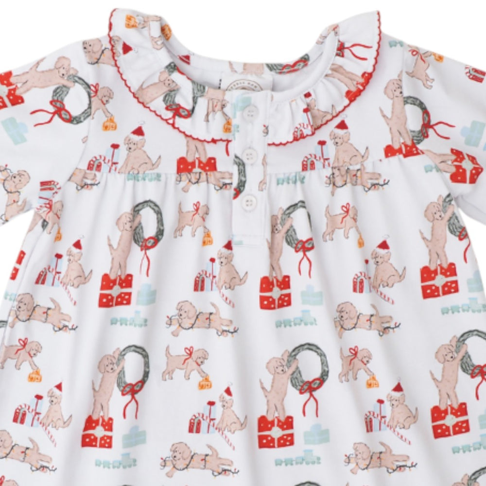 A white long-sleeve baby dress with a festive Christmas print featuring dogs, wreaths, gifts, and candy canes, finished with a ruffled collar and button placket, that store