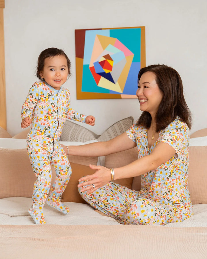 Woman and child in matching pajamas on a bed with abstract art in the background