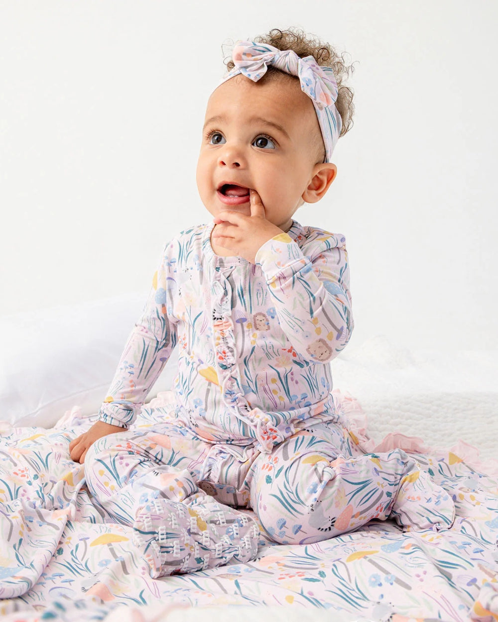 Baby wearing a colorful onesie with a headband on a white background