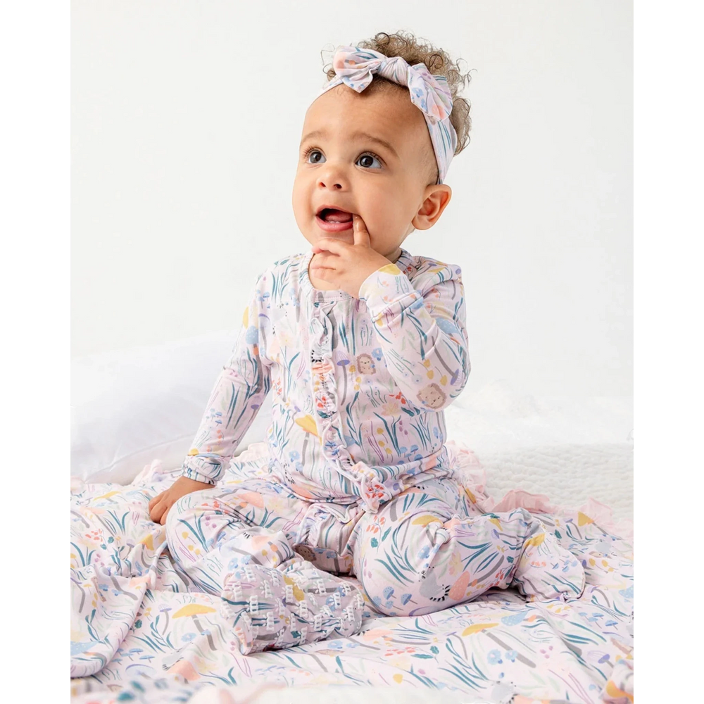 Baby wearing a colorful onesie with a headband on a white background