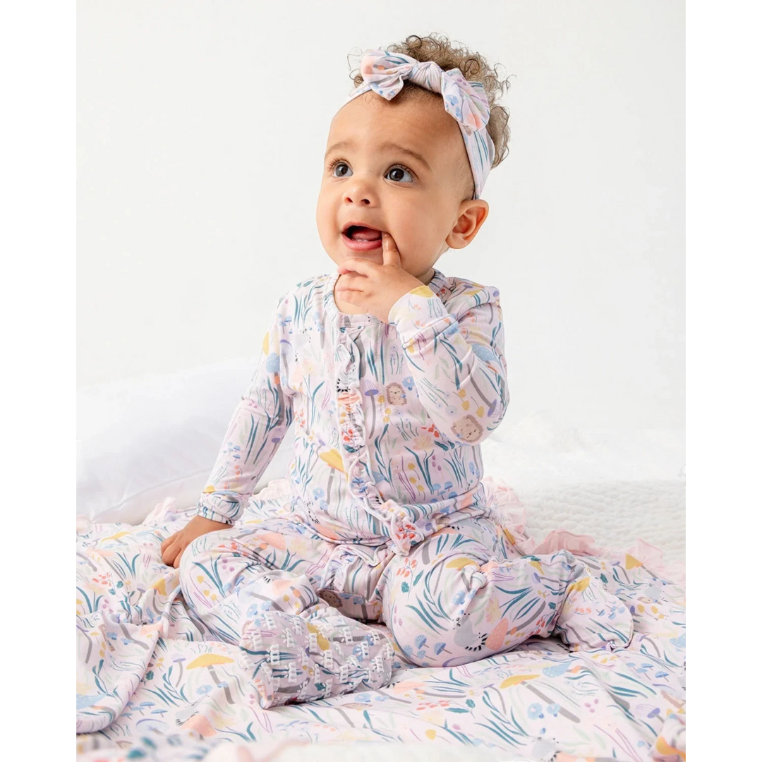 Baby wearing a colorful onesie with a headband on a white background
