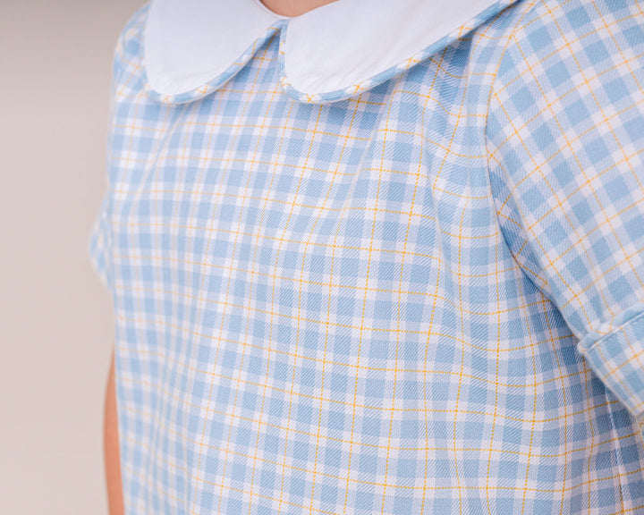 Blue and yellow checkered shirt with a white collar on a neutral background