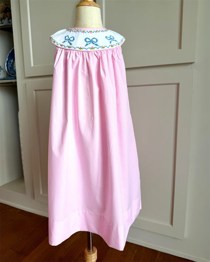 Pink dress with embroidered collar on a mannequin against a white cabinet background