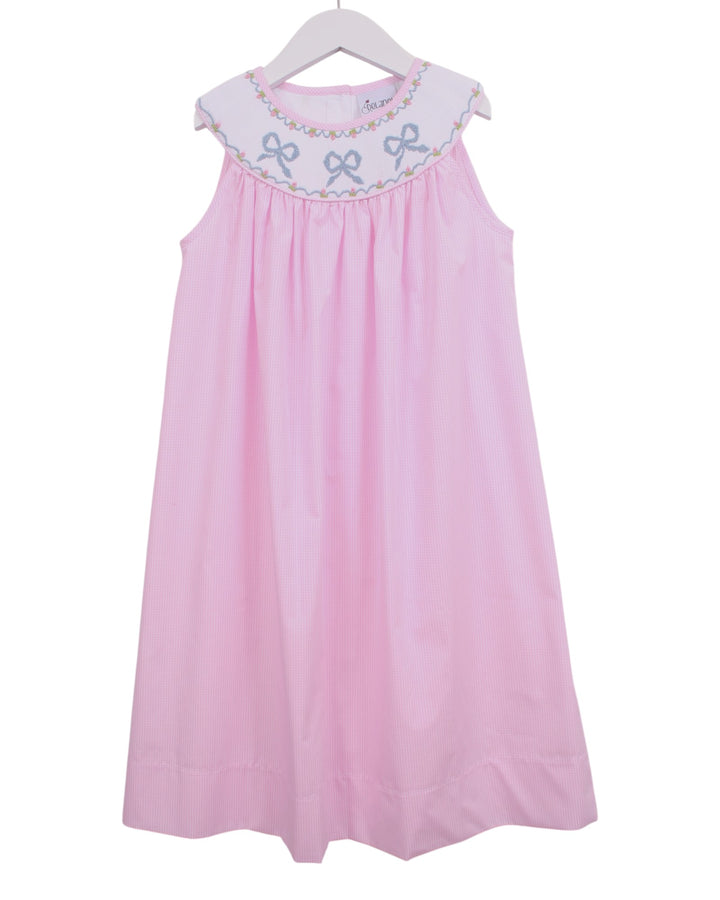 A pink sleeveless baby dress with a white embroidered yoke featuring blue bows and delicate floral details, hanging on a white hanger against a white background, that store