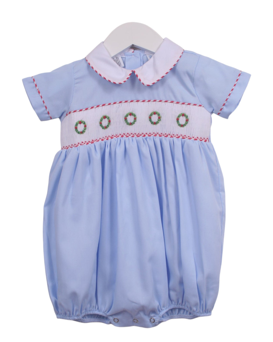 A light blue baby smocked romper with a white Peter Pan collar and a smocked chest panel featuring green wreath motifs and red stitching, displayed on a white hanger against a white background, that store