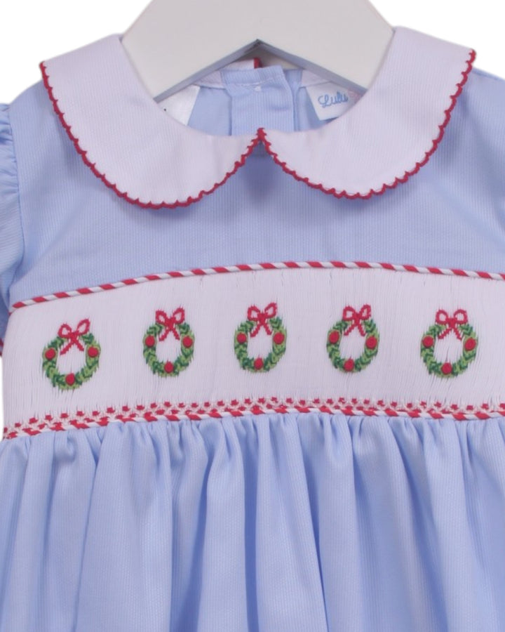 A light blue baby dress with a white Peter Pan collar trimmed in red, featuring a smocked horizontal band with four green and red embroidered wreaths, that store