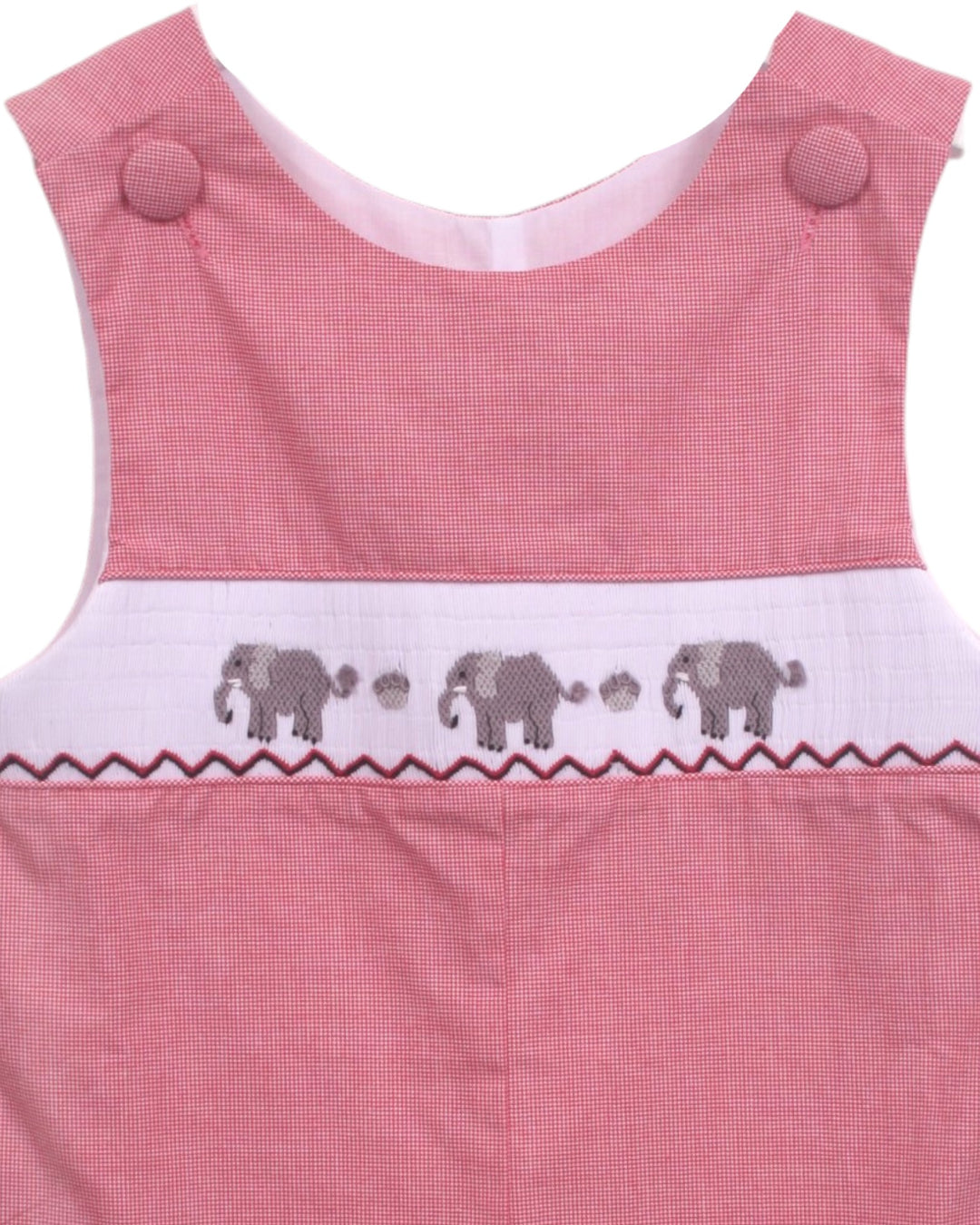 Close-up of a pink sleeveless garment, likely a baby romper or dress, featuring a white smocked band with embroidered gray elephants and paw prints, that store