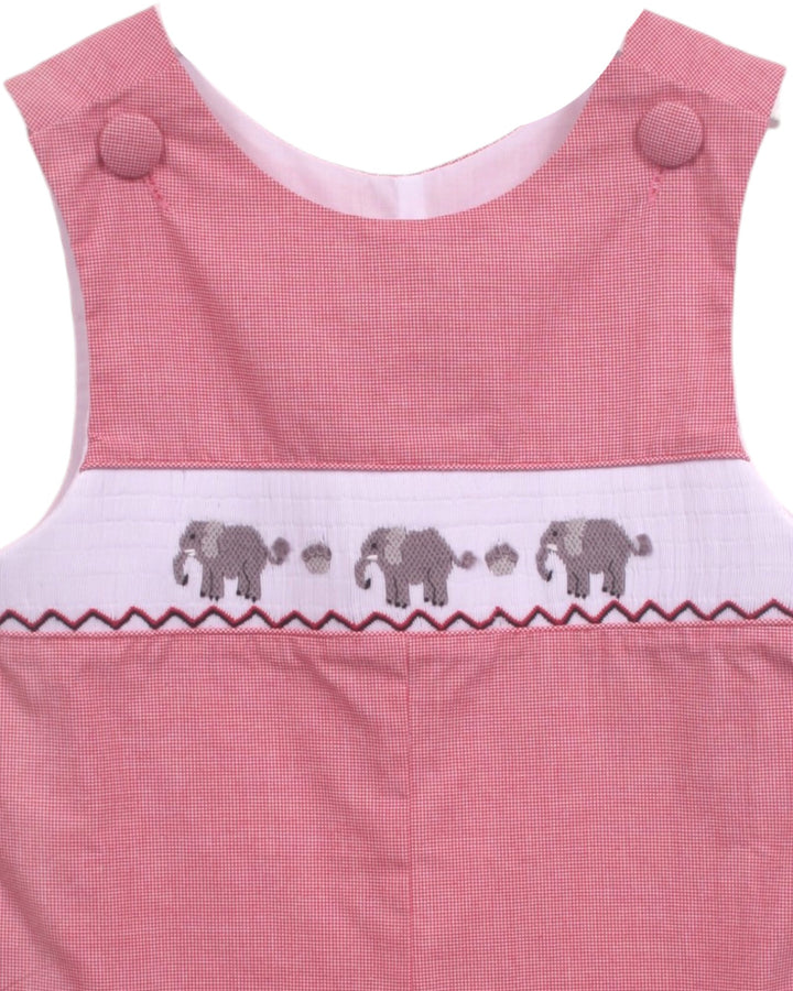 Close-up of a pink sleeveless garment, likely a baby romper or dress, featuring a white smocked band with embroidered gray elephants and paw prints, that store