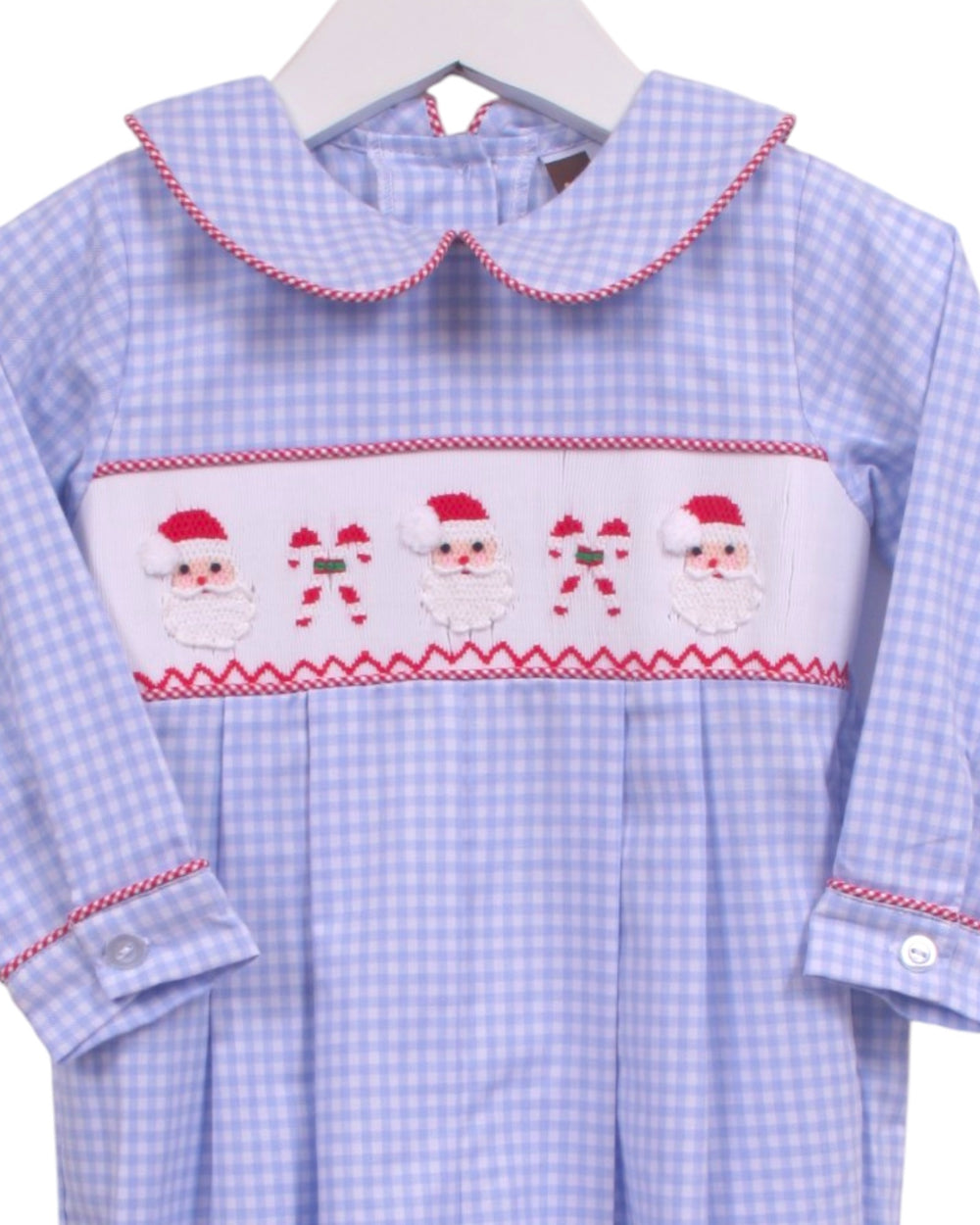A baby girl's long-sleeve dress in a light blue and white gingham pattern, featuring a white smocked chest panel with embroidered Santa Claus faces and candy canes, and red trim, that store