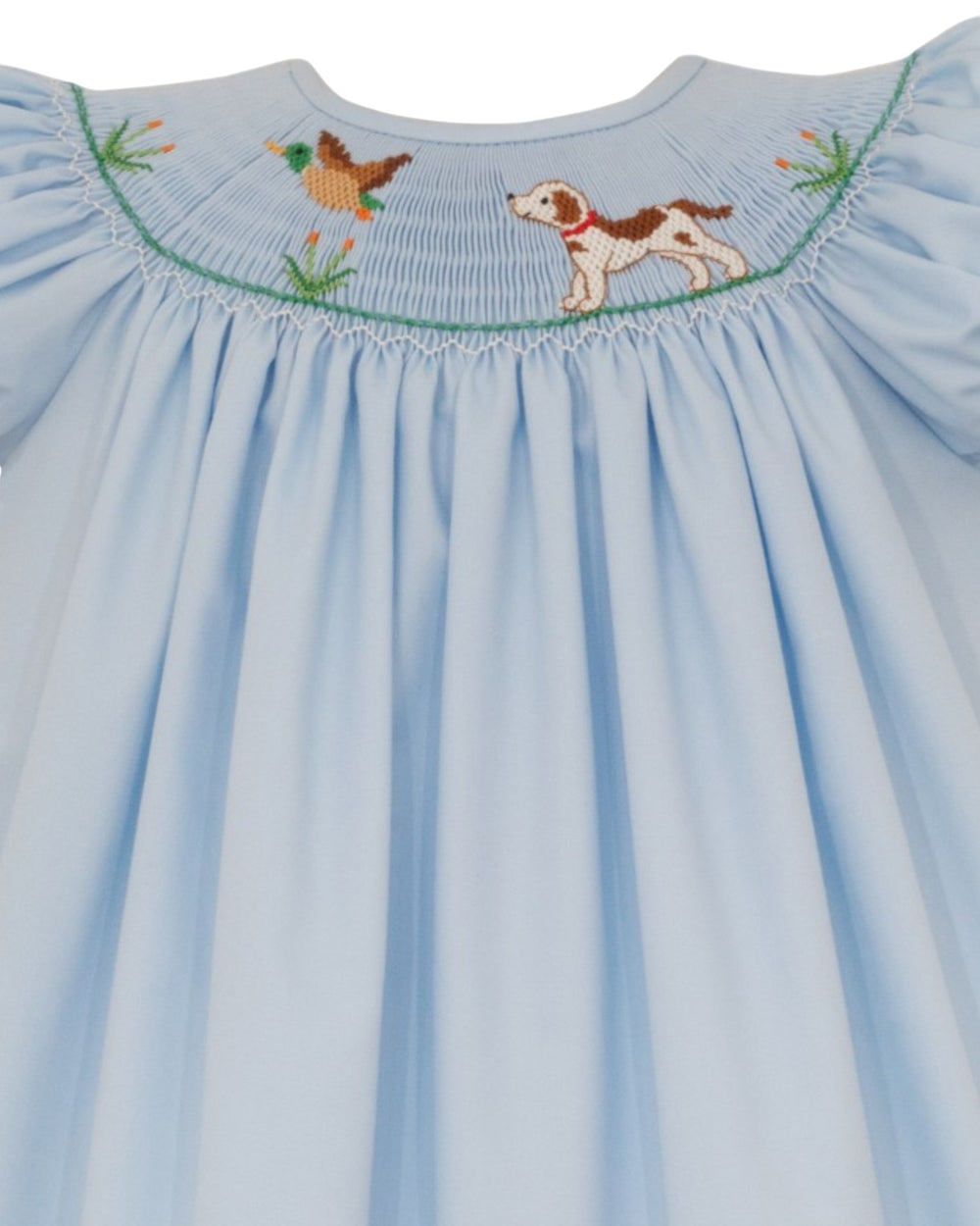 A light blue baby smocked dress featuring embroidered details of a brown and white dog and a duck at the neckline, set against a plain white background, that store