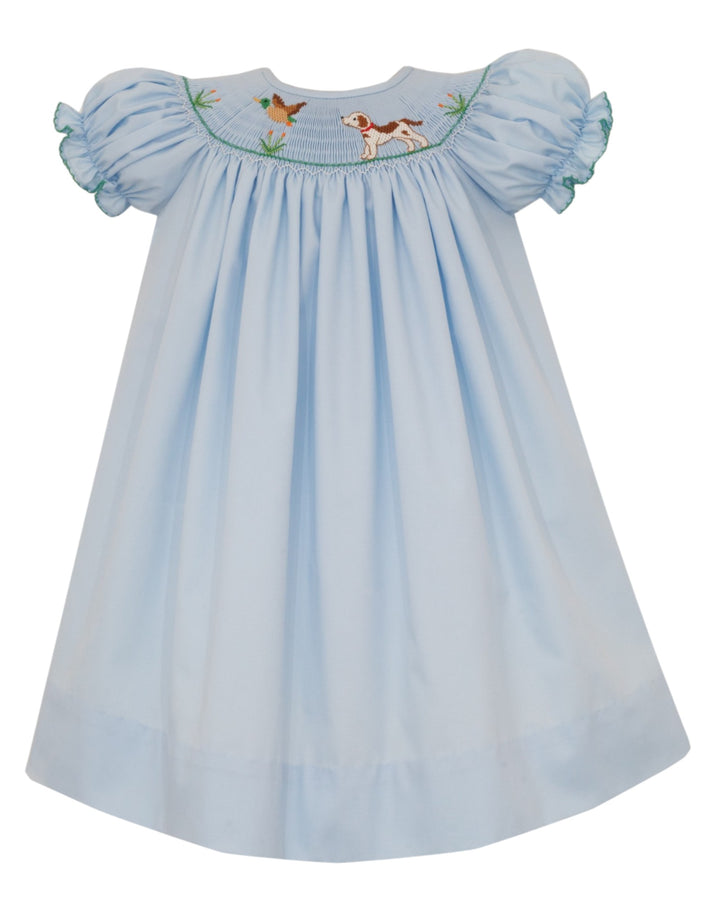 A light blue baby dress with short puff sleeves, featuring smocked detailing and embroidered birds and a dog on the chest, set against a plain white background, that store