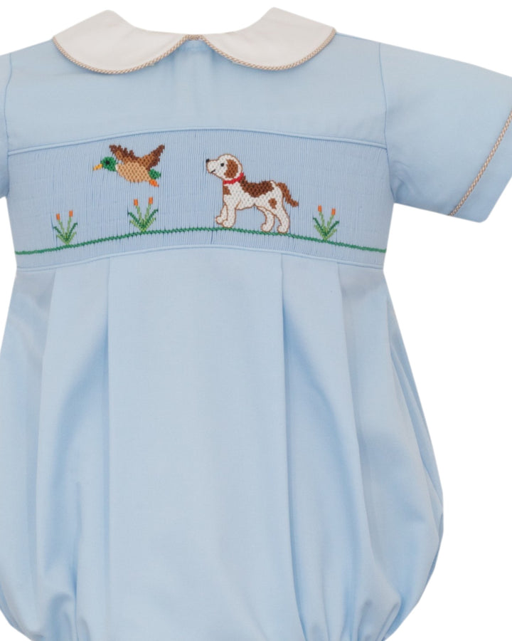 A light blue baby romper with a white Peter Pan collar and embroidered details of a duck and a dog on the chest, set against a plain white background, that store