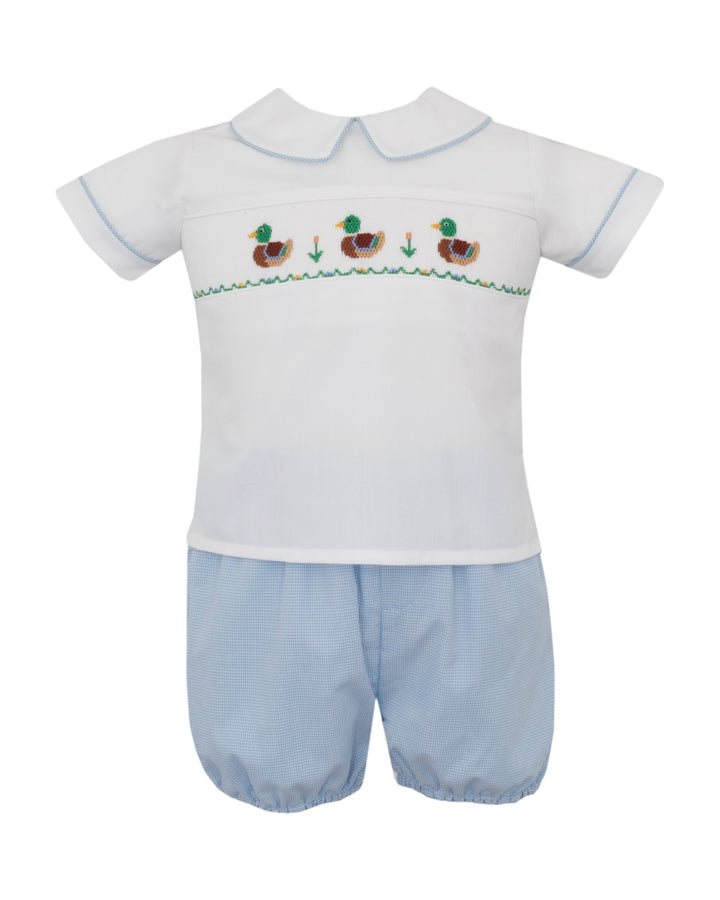 A baby two-piece outfit featuring a white short-sleeve smocked top with a Peter Pan collar and embroidered ducks, paired with light blue gingham bubble shorts, that store