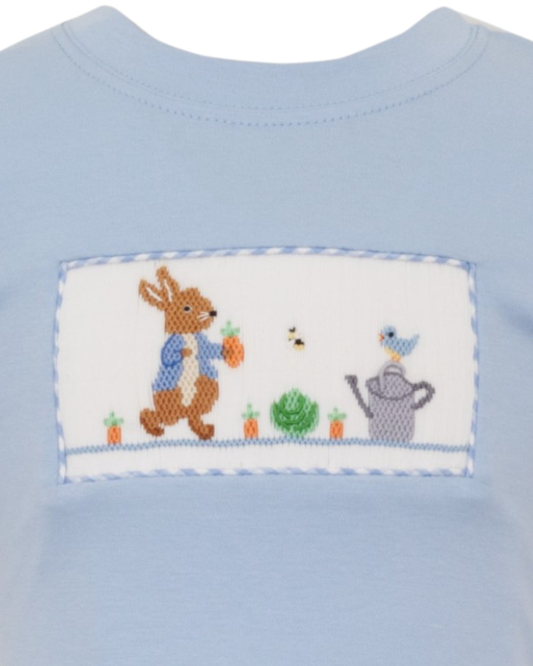 Light blue shirt with a embroidered design of a rabbit, bird, and watering can on a white background.