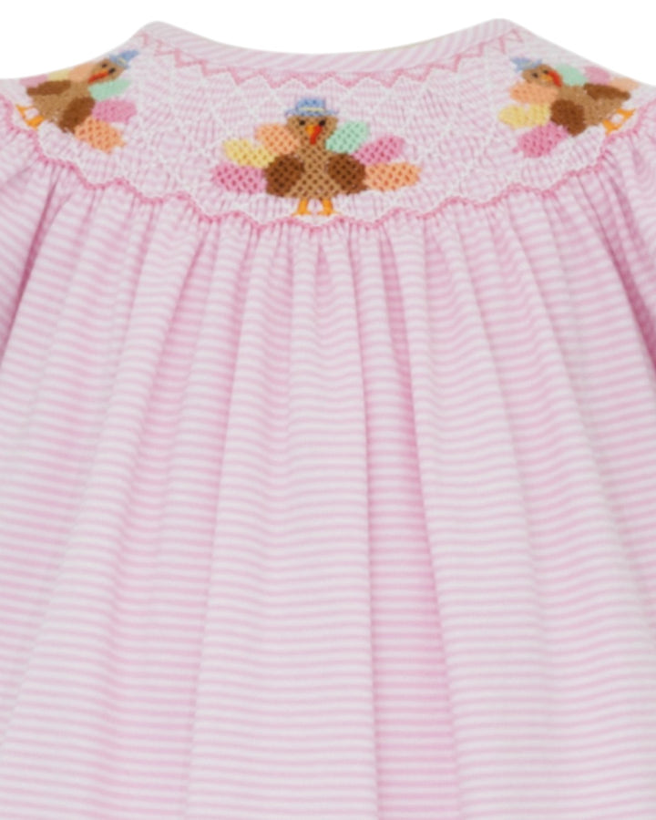 Pink dress with embroidered teddy bear design on a white background